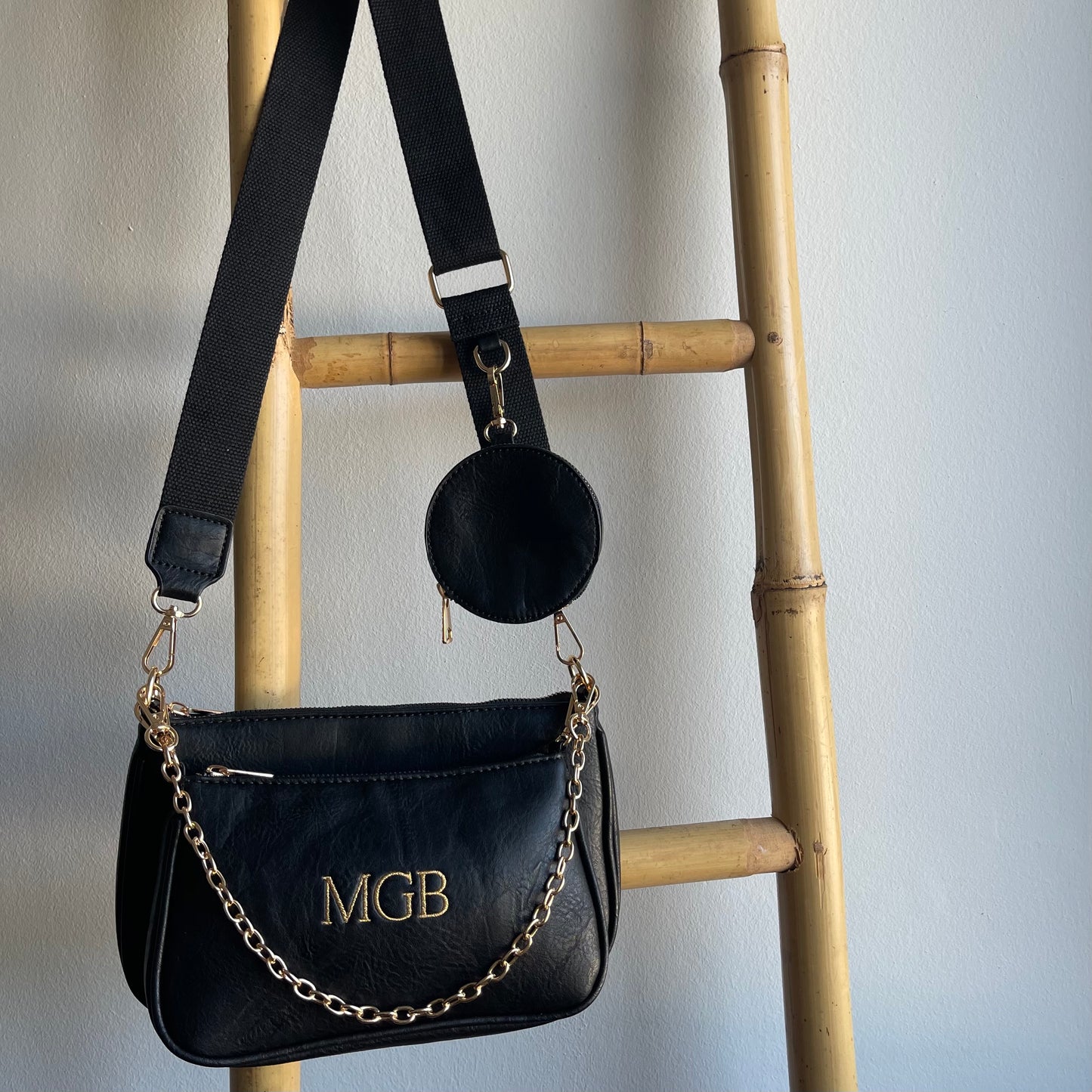 Bolso Multipochette liso negro personalizado con iniciales bordadas.