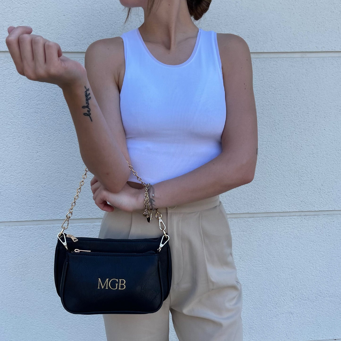 Bolso Multipochette liso negro personalizado con iniciales bordadas.