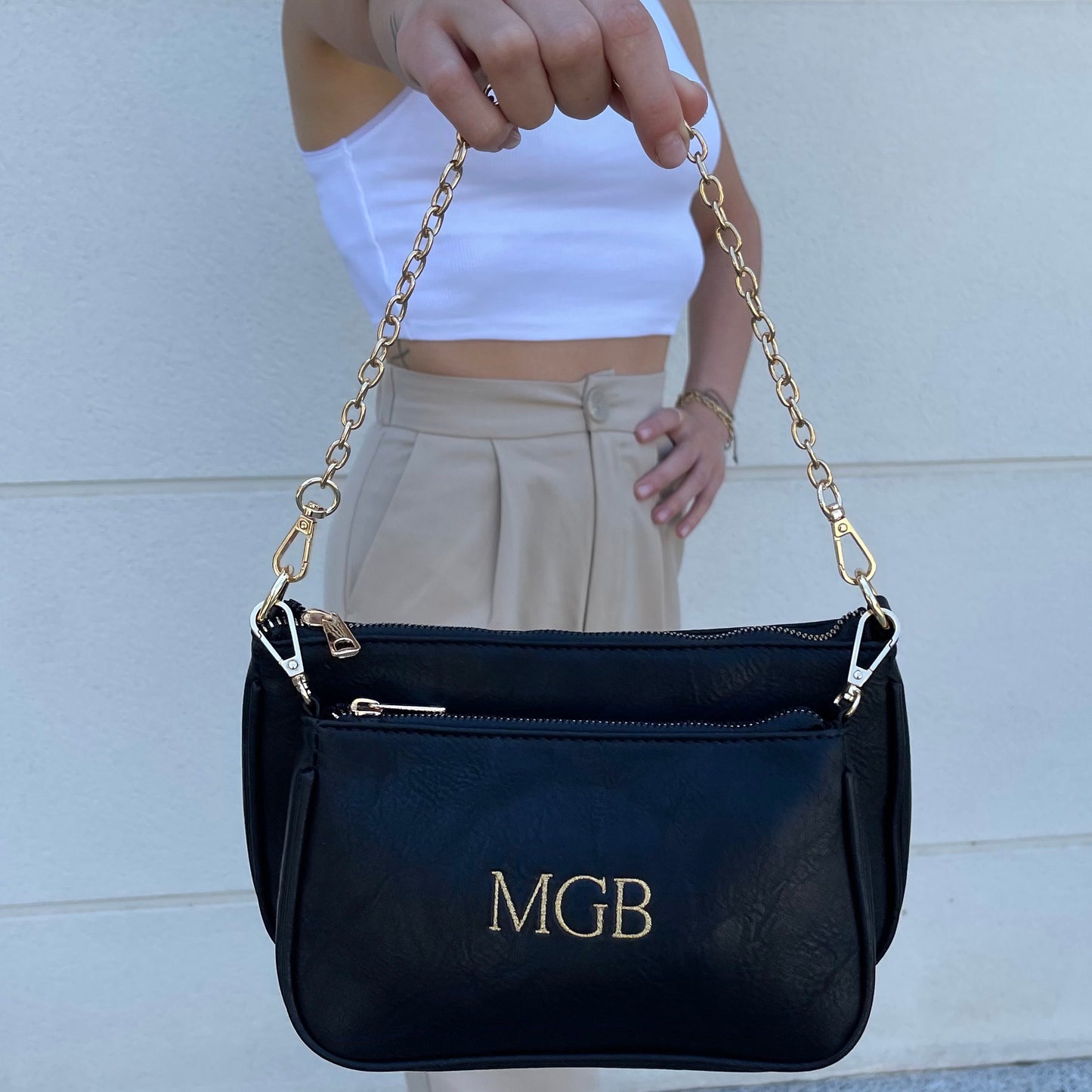 Bolso Multipochette liso negro personalizado con iniciales bordadas.