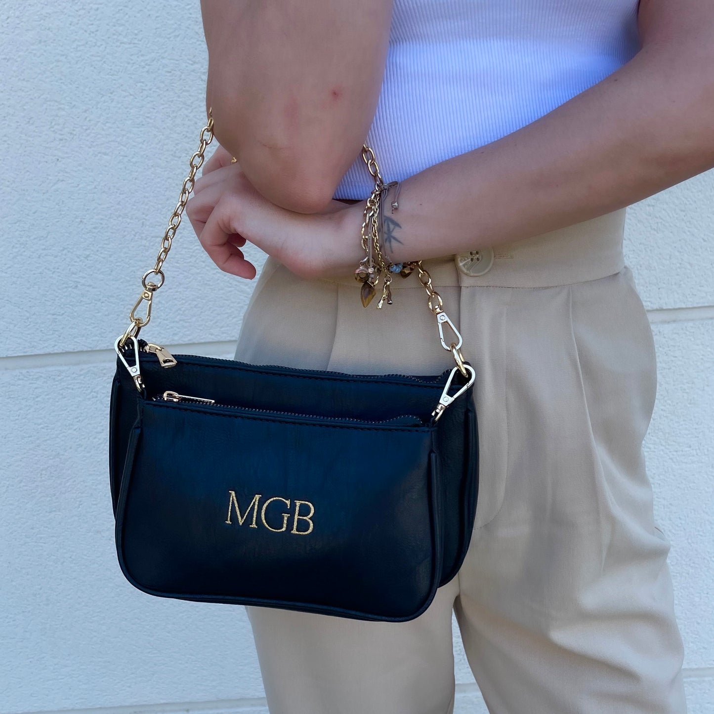 Bolso Multipochette liso negro personalizado con iniciales bordadas.
